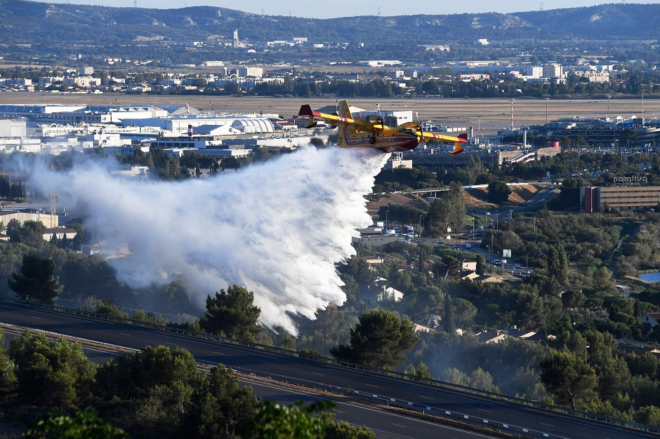A Canadair firefighting plane flies over the A7 motorway as it drops water over a fire which broke out in the industrial zone of Vitrolles, southeastern France. PHOTO: Reuters.