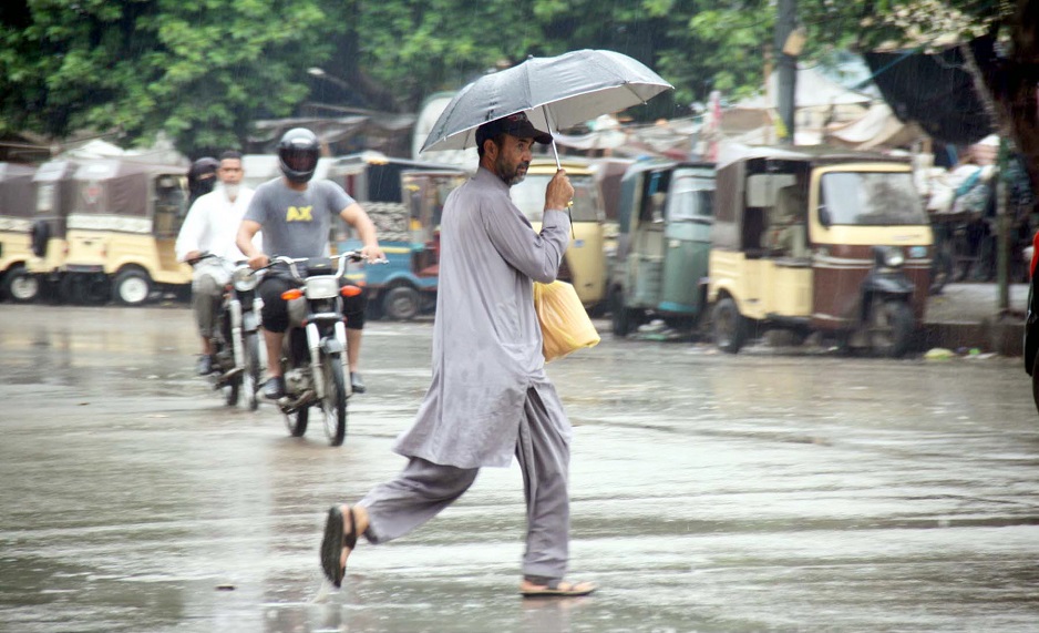 A man carries an umbrella to protect him from the downpour. PHOTO: APP