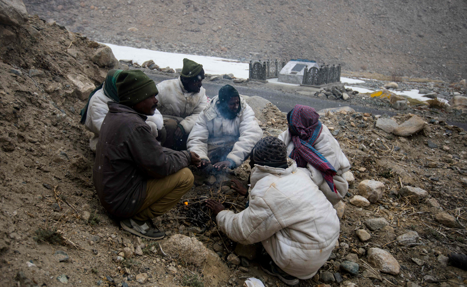 Road maintenance workers from India's low-lying eastern Jharkhand state warm up around a bonfire during a inclement weather while working along Pangong Lake road near the Chang La pass in northern India's Ladakh region of Jammu and Kashmir state. Photo: AFP