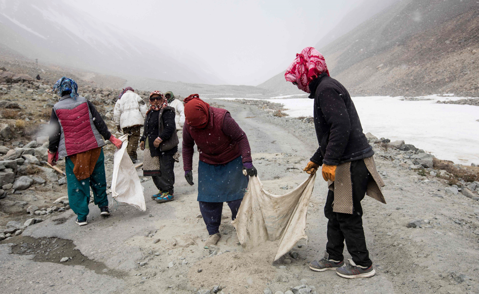 Local Ladakhi workers (foreground) along with road maintenance workers from India's low-lying eastern Jharkhand state carry out maintenance road works during inclement weather along Pangong Lake road in northern India's Ladakh region. Photo: AFP