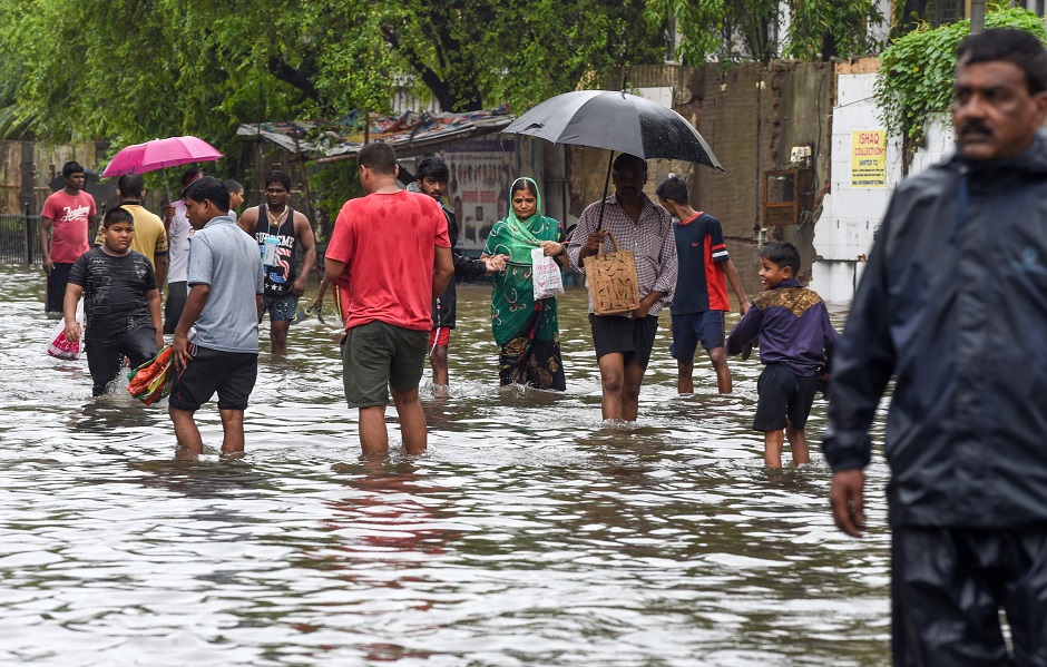 Pedestrians make their way on a flooded road after heavy monsoon rains in Mumbai. PHOTO: AFP
