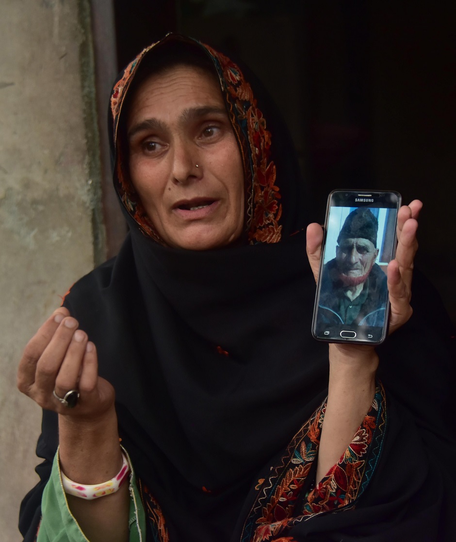 An Indian Kashmiri refugee Khadija Bibi shows a picture of her late father on her mobile phone as she speaks during an interview with AFP in the Manak Paiyan refugee camp near Muzaffarabad, Kashmir. (Photo: SAJJAD QAYYUM / AFP)