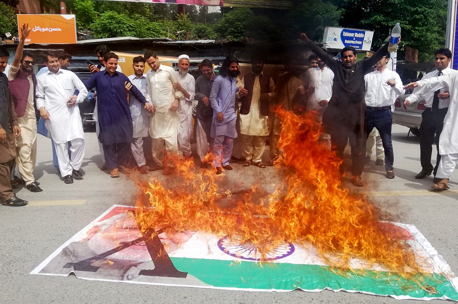 Kashmiris chant slogans beside a burning Indian flag with a photograph of Indian Prime Minister Narendra Modi during a protest in Muzaffarabad, the capital of Pakistan controlled Kashmir. PHOTO: AFP