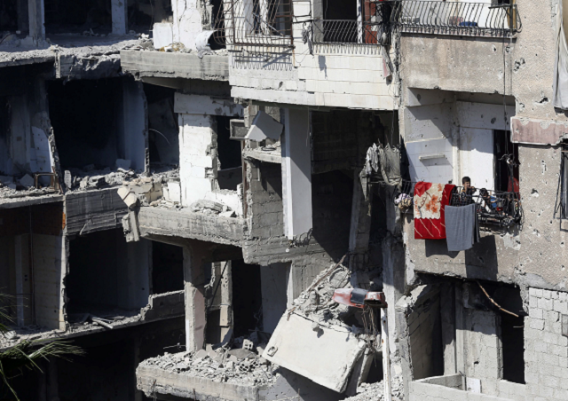 syrian children stand on a balcony of a destroyed building in harasta on the outskirts of the syrian capital damascus photo afp