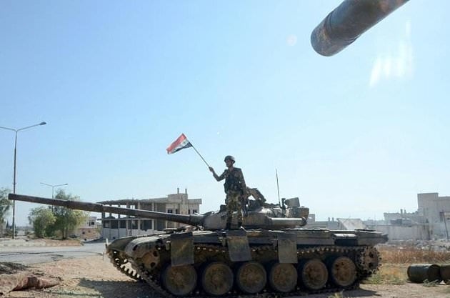 a syrian soldier waves a national flag atop a tank in the strategic town of khan sheikhun on saturday photo afp