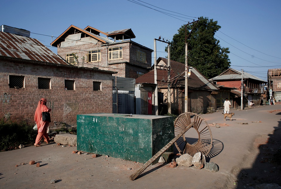 A Kashmiri woman walks past a blockade put up by residents to prevent Indian security force personnel from entering their neighborhood during restrictions. PHOTO: REUTERS