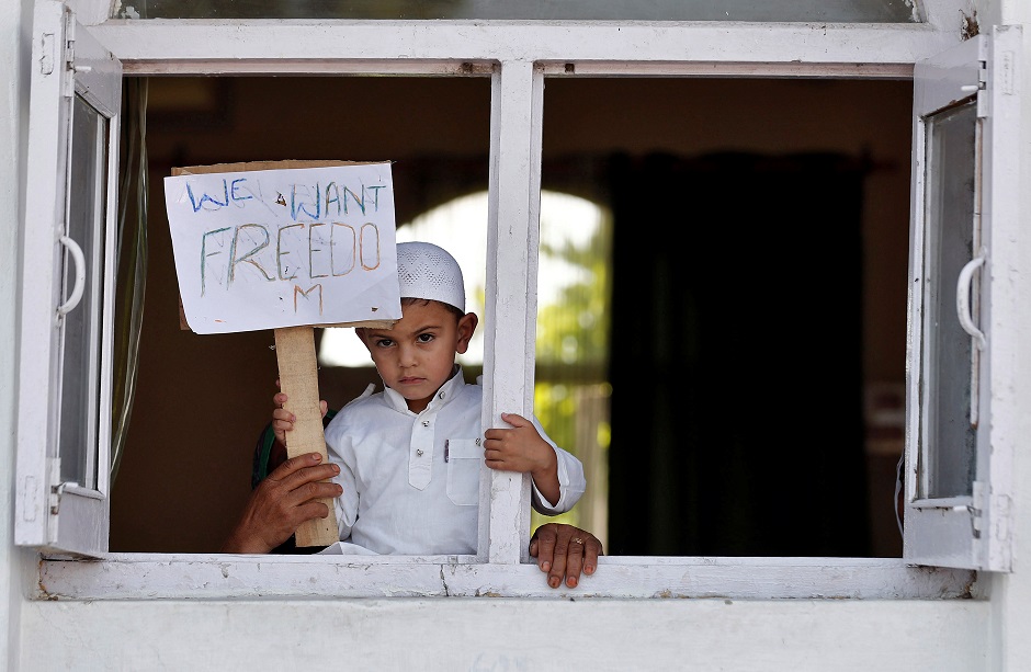 A Kashmiri boy displays a placard from a window at a protest site after Friday prayers during restrictions. PHOTO: REUTERS 