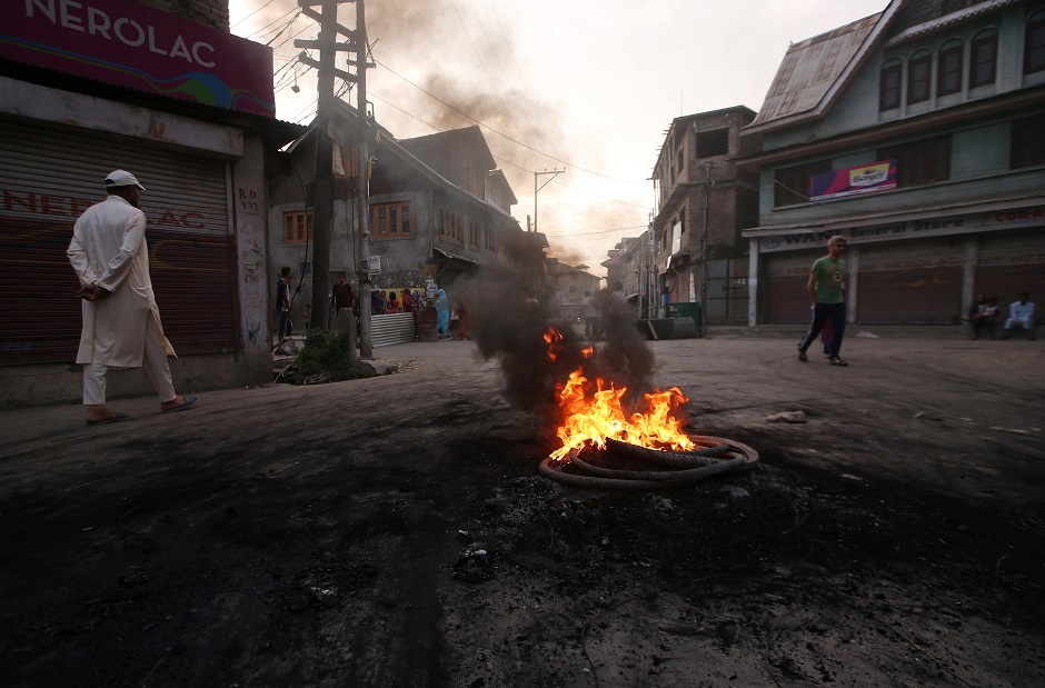 Kashmiri people walk past burning tyres during a protest after the scrapping of the special constitutional status for Kashmir by the Indian government, in Srinagar. PHOTO: REUTERS