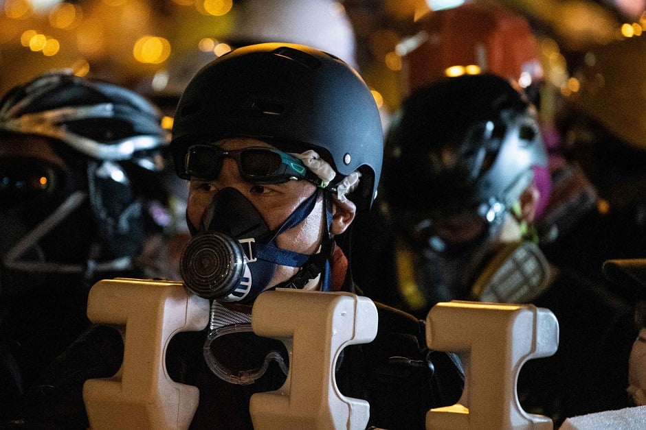 A group of protesters wearing helmets and masks gather in a street of Tsim Sha Tsui district in Hong Kong in the latest opposition to a planned extradition law that has quickly evolved into a wider movement for democratic reforms. PHOTO: AFP