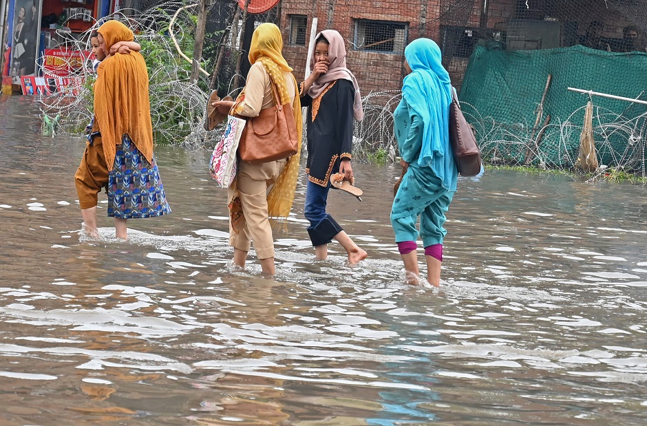 Kashmiri pedestrians walks through floodwaters on a waterlogged road during rainfall in Srinagar. PHOTO: AFP
