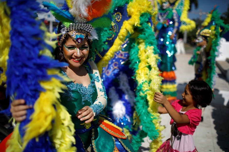 A girl plays with the costume of a performer prior to the opening parade of the festivities of El Divino Salvador del Mundo. PHOTO: Reuters