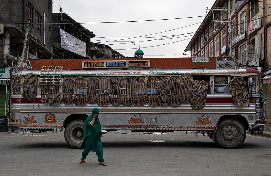 A Kashmiri woman walks past a bus used as a road block by Indian security personnel in Srinagar. Photo: REUTERS