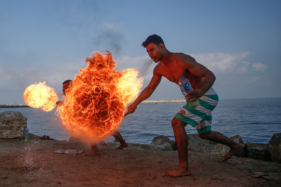 Palestinian men perform fire breathing on the beach as an entertainment for children during the summer vacation in Gaza City. PHOTO: Reuters