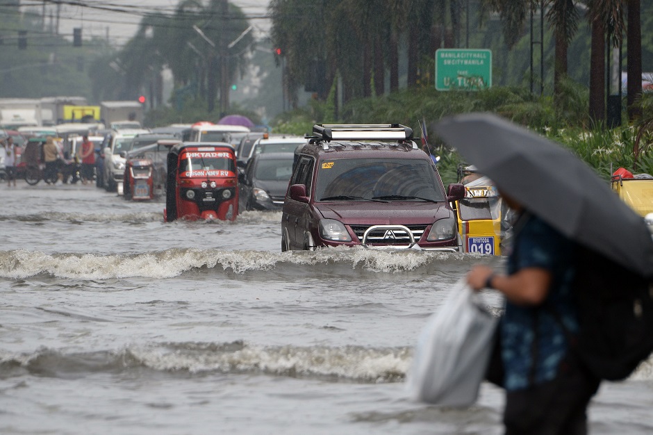 Motorists and commuters negotiate a flooded street, caused by a heavy downpour brought about by the southwest moonson, in Manila. PHOTO: AFP