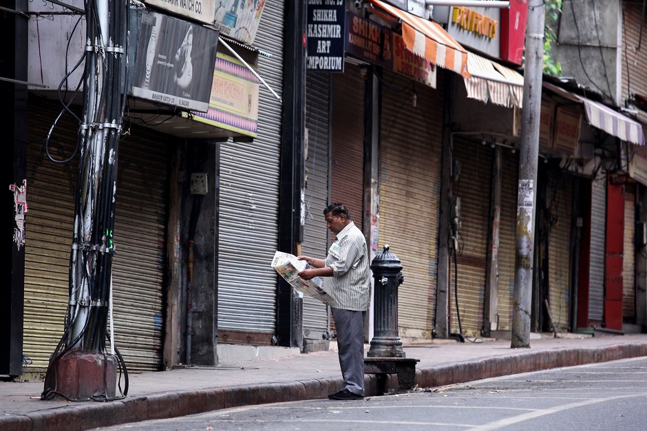 A man reads a newspaper standing in front of closed shops in Jammu on August 6, 2019. (Photo: Rakesh BAKSHI / AFP)