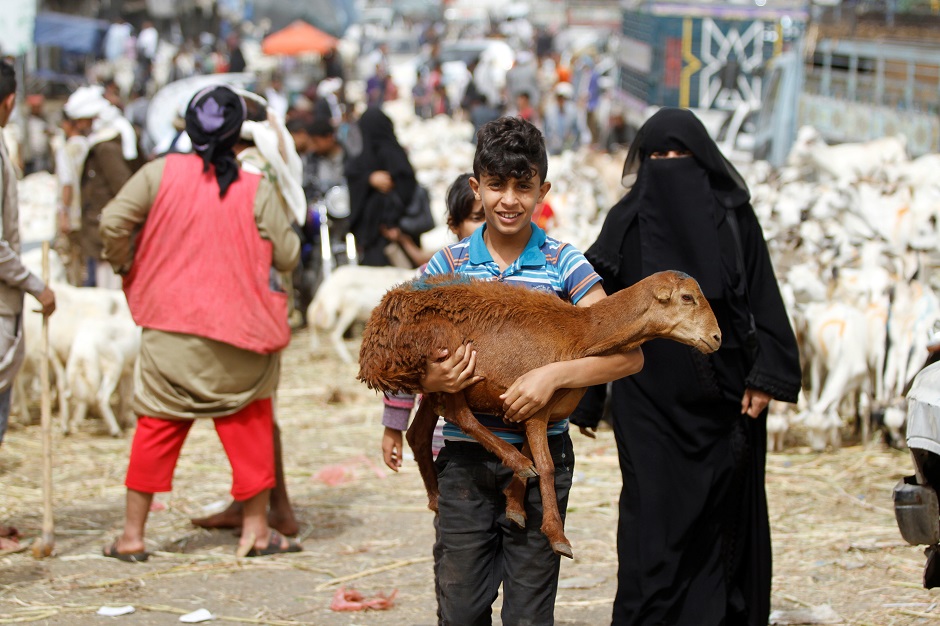 A boy carries a goat at a livestock market where people buy sacrificial animals ahead of the Eid al-Adha celebrations in Sanaa, Yemen. PHOTO: Reuters