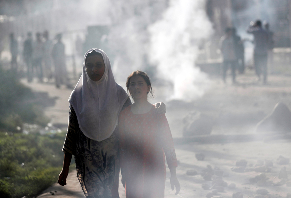 Kashmiri girls walk amidst smoke during clashes between Indian security forces and protestors in Srinagar on August 23, 2019.