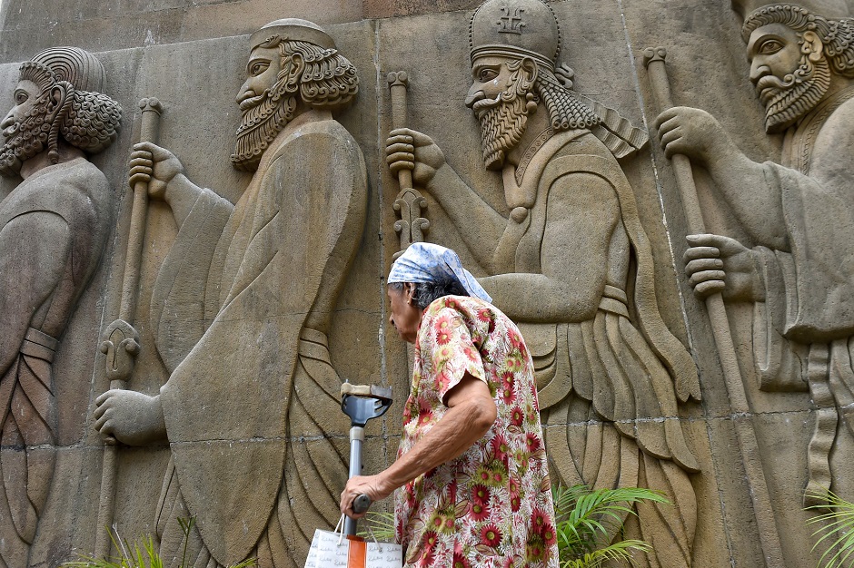 An elderly Parsi woman walks past relief figures of knights at a fire temple during Navroze, the Parsi New Year, in Mumbai. PHOTO: AFP