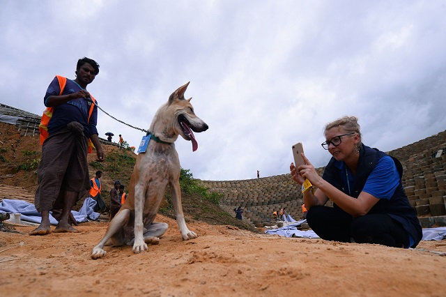 World Food Programme (WFP) official Gemma Snowdon (L) taking images to post on social media of Foxtrot, a dog with the WFP K9 unit, in the Kutupalong camp for Rohingya refugees, July 23, 2019. PHOTO: AFP