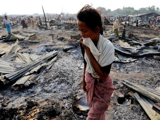 A woman walks among debris after fire destroyed shelters at a camp for internally displaced Rohingya Muslims in the western Rakhine State near Sittwe in Myanmar. PHOTO: REUTERS