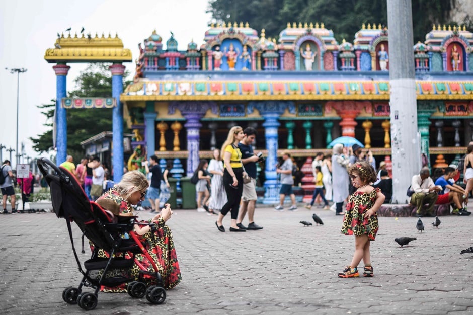 A tourist takes pictures of a child at a temple in Batu Caves, near Kuala Lumpur. PHOTO: AFP
