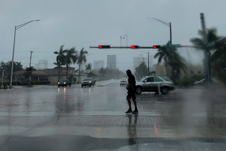 A man crosses the street during a pouring rain in Fort Lauderdale. PHOTO: REUTERS