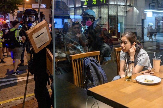  a  woman sits in a restaurant as pro-democracy protesters gather on a street in the Wan Chai district in Hong Kong. - With pro-democracy protests now in their fourth month, Hong Kong has been left counting the cost, with the city s tourist industry battered and businesses forced to lay off staff as they struggle to stay afloat. PHOTO: AFP 