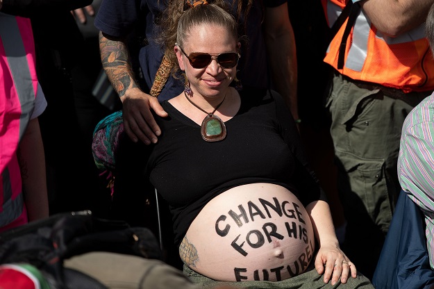 A pregnant activist with a message on her belly protests in front of Parliament during a climate strike protest march in Wellington. PHOTO: AFP 