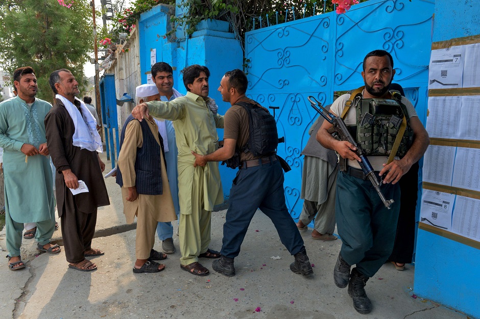 A security force personnel checks a man outside a polling station in Jalalabad. PHOTO: AFP