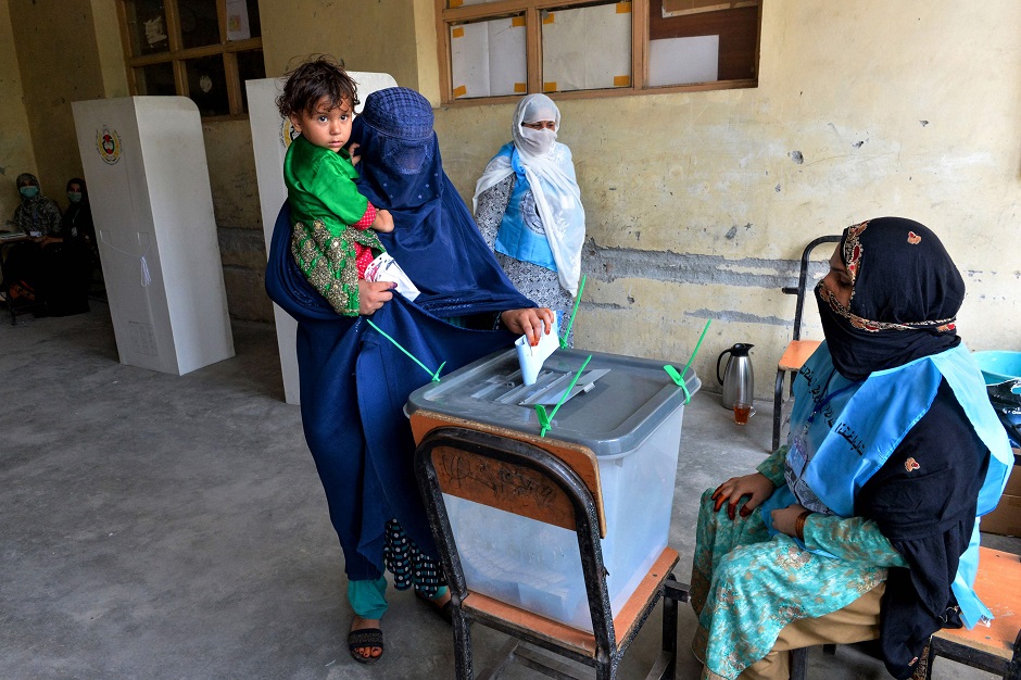 A woman holds her child as she casts her vote at a polling station in Jalalabad. PHOTO: AFP