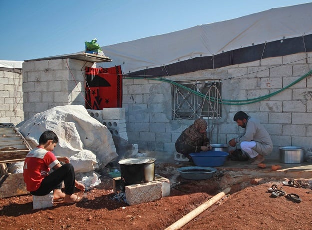 Abu Salloum and members of his family cook at a camp for displaced Syrians in Atme. (Photo: AFP)