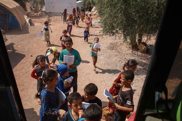 Displaced Syrian children queue for their turn outside the bus (Photo: AFP)