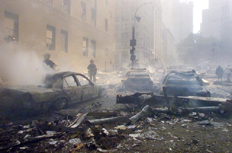 Cars smolder in the street as the destroyed World Trade Center burns in New York, September 11, 2001. PHOTO: Reuters 