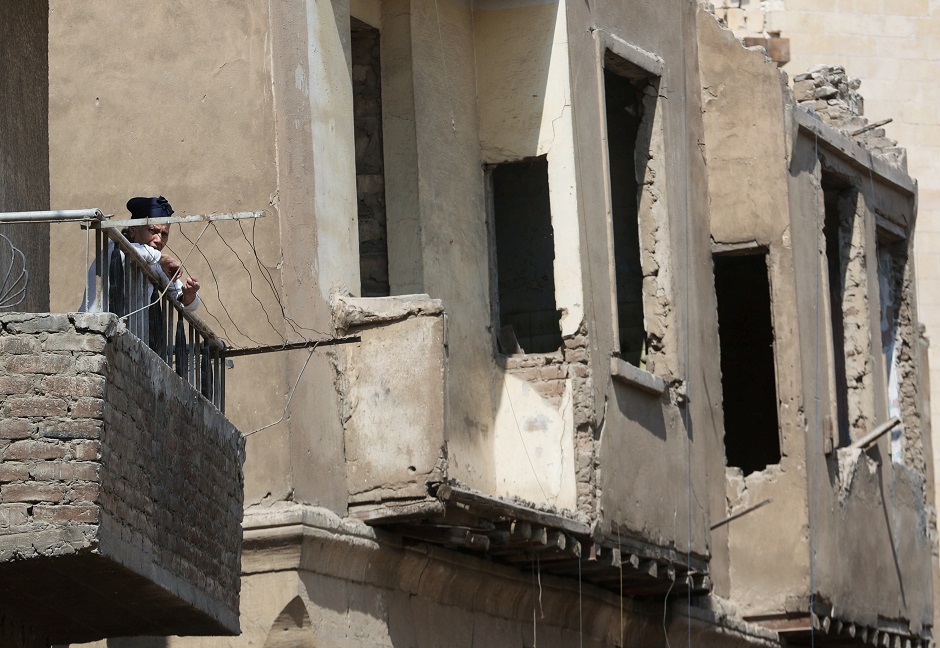 A woman stands in a balcony with old houses in the background at Darb al-Labbana hillside neighbourhood in Cairo, Egypt. PHOTO: REUTERS