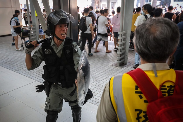 A riot police officer confronting a group of 