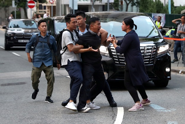 A protester is escorted by undercover police officers after he tried to stop Hong Kong Chief Executive Carrie Lam's motorcade in Hong Kong. PHOTO: Reuters