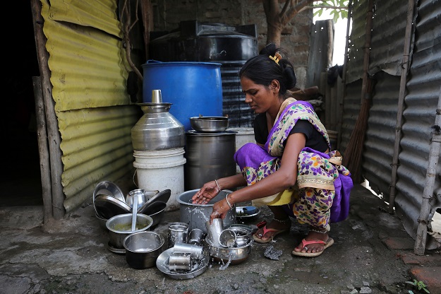 A woman washes utensils outside her house in Aurangabad. PHOTO: Reuters