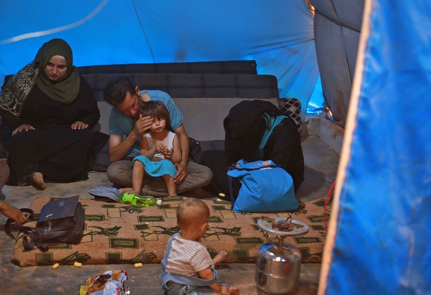 Jaber Karawan pats his daughter's head as he sits with his wife Walaa and others inside a shelter at a camp for displaced Syrians in Atme in the northwestern Idlib province, near the borther with Turkey. (Photo: AFP)
