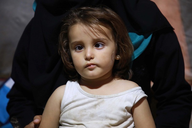 Mirale, the daughter of Syrian Jaber Karawan and his wife Walaa, who suffers from an eye disease, sits in the lap of her mother. (Photo: AFP)