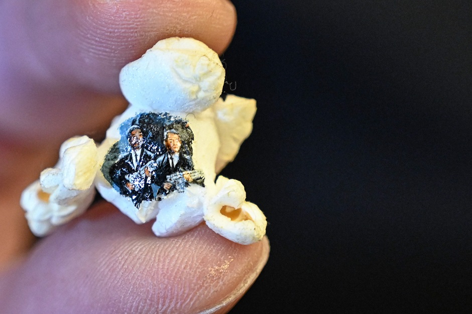 A picture taken on August 23, 2019 shows two armed men in black painted on a popcorn by Turkey's micro artist Hasan Kale in Istanbul. - His canvas could be anything from match sticks, seeds to razors and crown corks. PHOTO: AFP