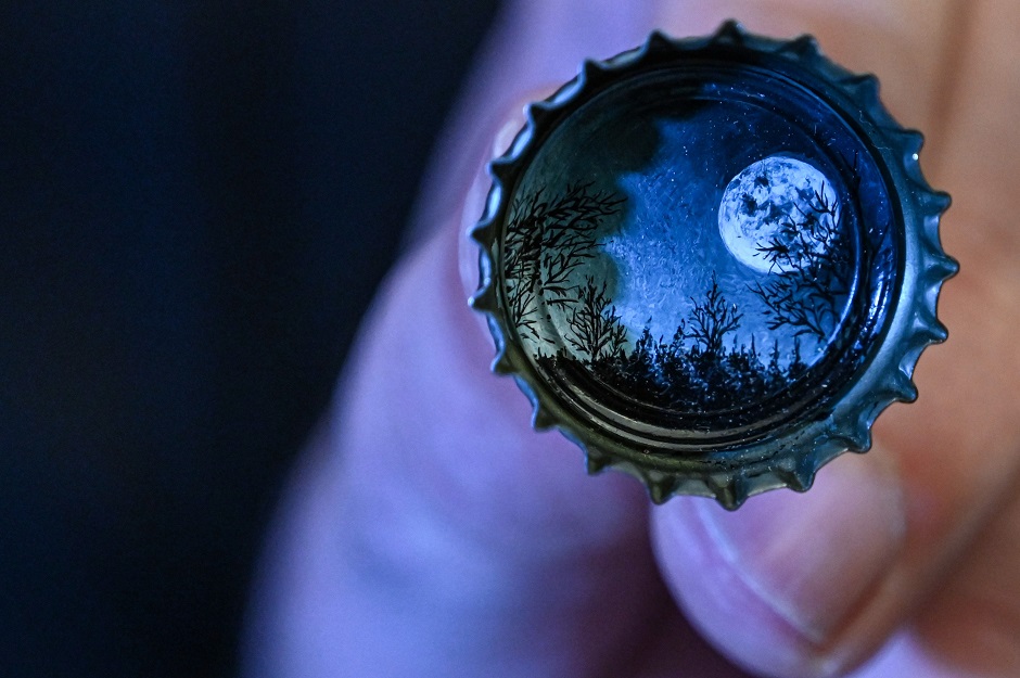A picture taken on August 23, 2019 shows a moon landscape painted on a bottle cap by Turkey's micro artist Hasan Kale in Istanbul. PHOTO: AFP