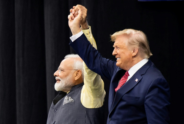 US President Donald Trump and Indian Prime Minister Narendra Modi raise their arms together at a joint rally in Houston. PHOTO: AFP