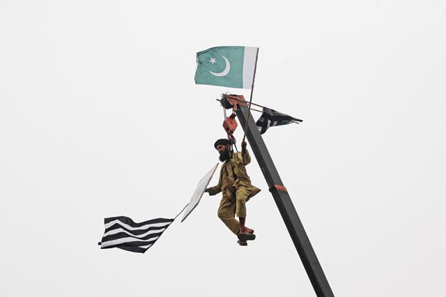 a jui f supporter is seen on crane holding the party 039 s and national flags in lahore on wednesday photo reuters