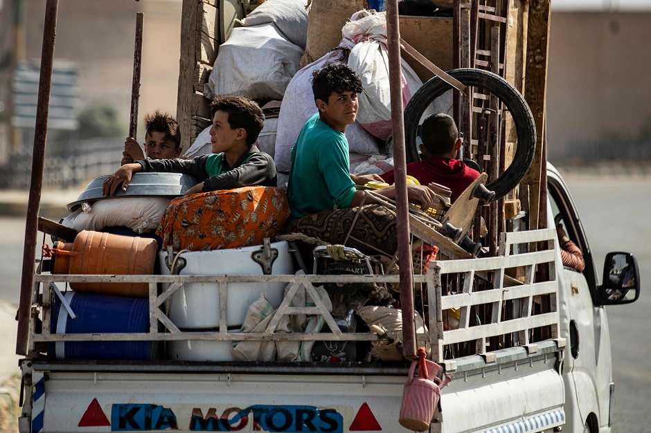 Displaced Syrians sit in the back of a pick up truck. PHOTO: AFP
