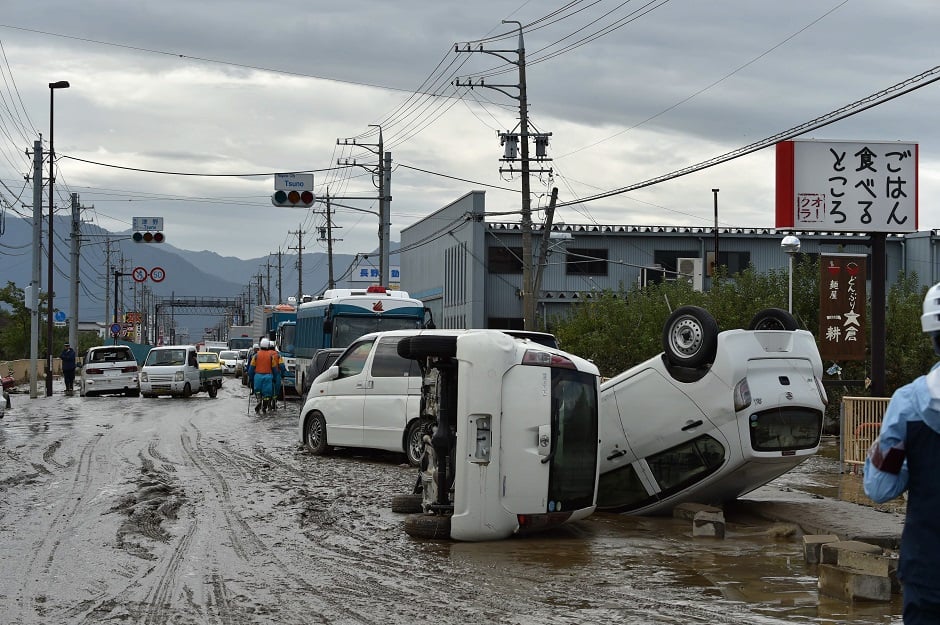 Overturned vehicles sit on the side of a muddy road in the aftermath of Typhoon Hagibis. PHOTO: AFP