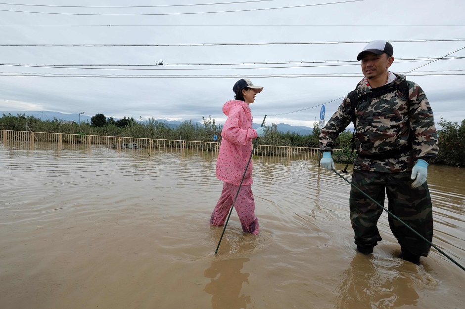 A man wades through floodwaters with items salvaged from his home. PHOTO: AFP