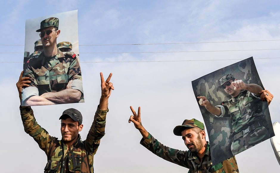 Syrian government soldiers hold up portraits of President Bashar al-Assad. PHOTO: AFP