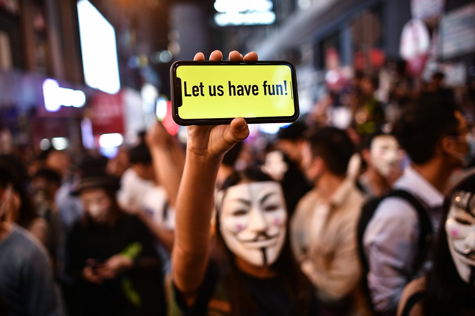 A person displays a message on a mobile phone in front of a line of policemen. PHOTO: AFP