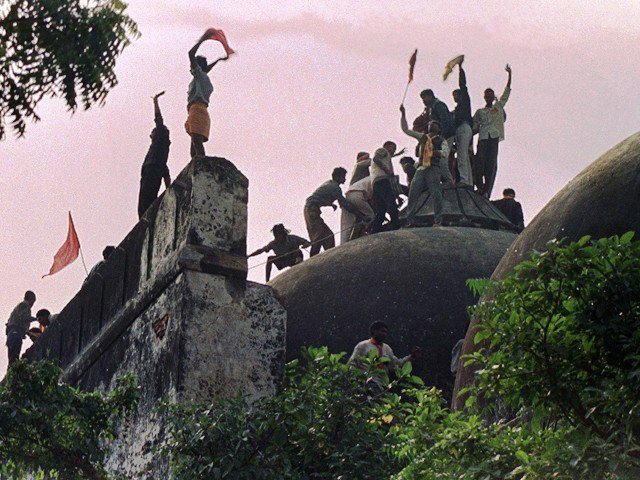 A photo taken on December 6, 1992 shows Hindus  shouting and waving banners as they stand on the top of a stone wall and celebrate the destruction of the 16th Century Babri Mosque in Ayodhya. PHOTO: AFP