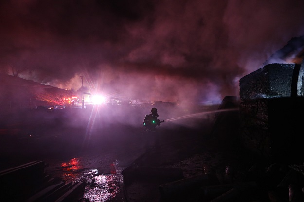 A firefighter works at an industrial facility heavily damaged by the Tick Fire. PHOTO: AFP